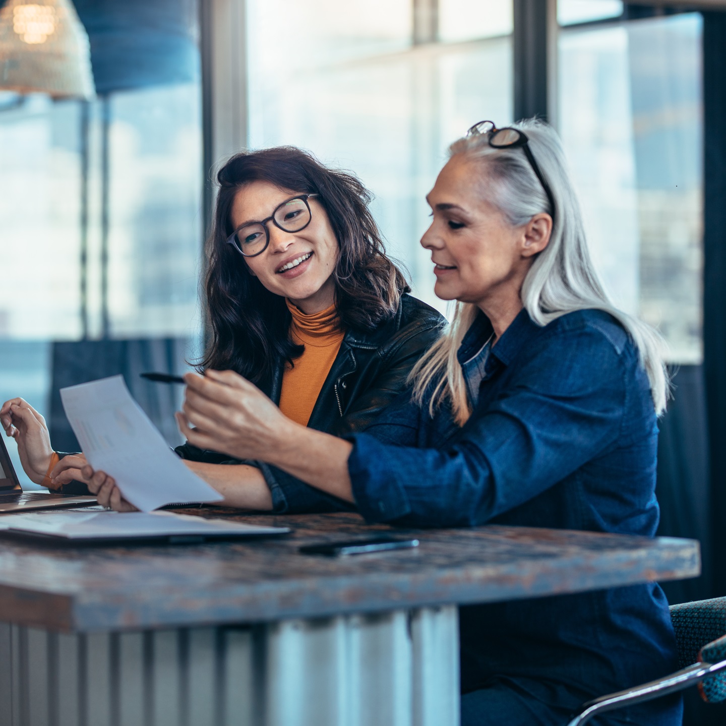Two women analyzing documents at office content-image