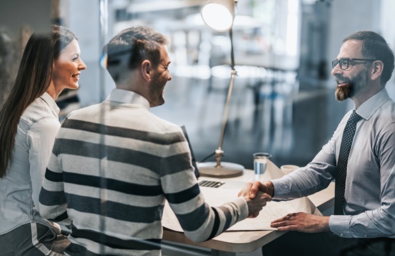 Happy couple shaking hands with real estate agent in the office. content-image
